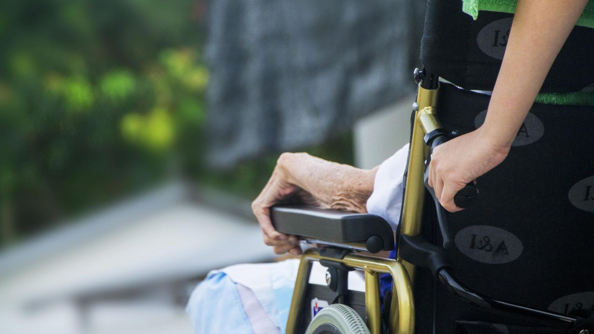 Arm of elderly woman resting on arm rest of wheelchair