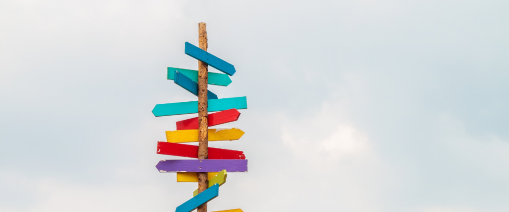 Multi colored arrows pointing in different directions against a cloudy sky